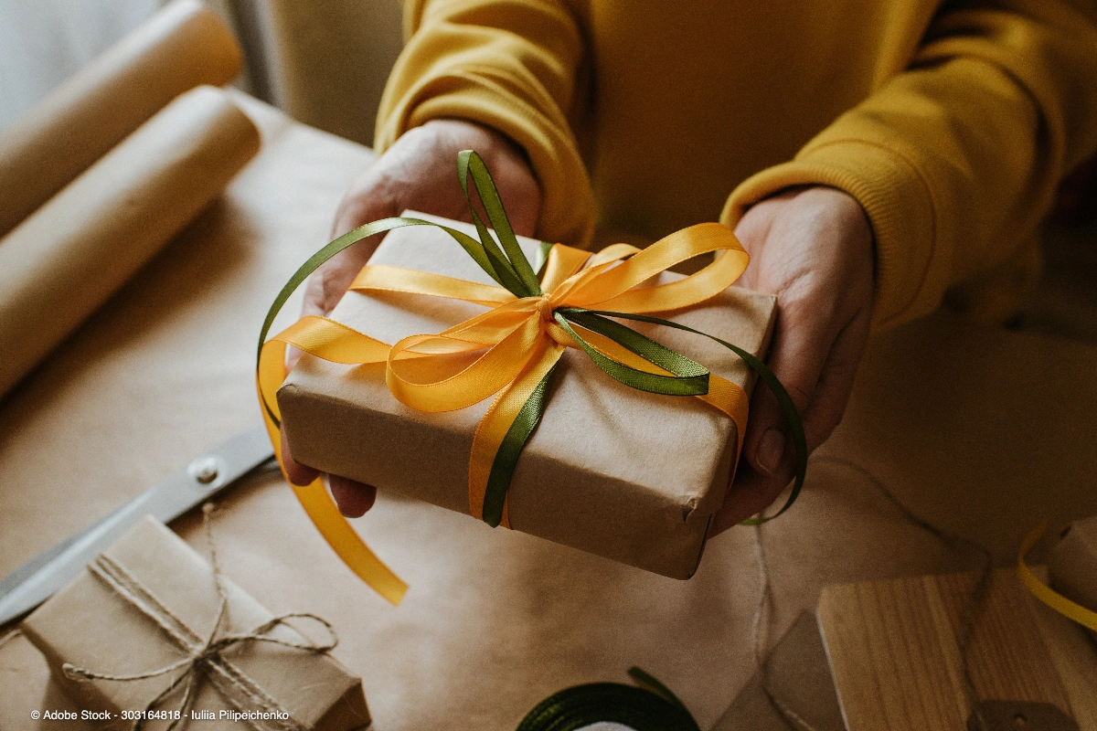 Eine Person überreicht ein liebevoll verpacktes Präsent mit Schleifen, passend zum Thema Ruhestand Geschenk Frau für besondere Anlässe.